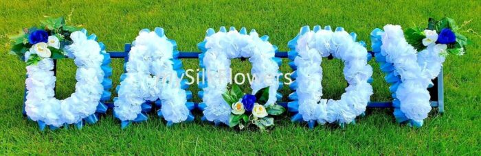 **DADDY Artificial Silk Funeral Tribute – Custom 5-Letter Name Flower Wreath (AUNTY Option)** Honor the memory of your loved one with this beautifully handcrafted **Artificial Silk Funeral Tribute Wreath**. Featuring a personalized 5-letter name, such as “DADDY” or “AUNTY,” this flower wreath is a meaningful and lasting tribute. Expertly made with premium artificial silk flowers, it offers a lifelike appearance and a thoughtful design, perfect for graveside or memorial displays. --- ### **Key Features:** #### **Personalized Name Tribute** - Customize your tribute with any **5-letter name**, including “DADDY,” “AUNTY,” or a name of your choice. - Each letter is adorned with vibrant artificial silk flowers, ensuring a visually striking and heartfelt tribute. #### **Premium Silk Flowers** - Crafted from high-quality **artificial silk carnations**, this wreath offers lasting beauty without the need for maintenance. - Enhanced with elegant **ribbon edging** and posy clusters, it adds a refined and personal touch. #### **Choice of Colors** - Select from **8 carnation colors** and **14 ribbon colors** to create a tribute that reflects the personality and style of your loved one. - Posy clusters are available in coordinating or contrasting colors to complete the design. #### **Ideal Dimensions** - Each tribute measures **XX inches wide x XX inches high**, providing a bold and graceful display for graveside or memorial settings. - Comes with a **florist frame stand** for easy setup and stability. #### **Complimentary Message Card** - Includes a **free message card and holder**, allowing you to express your love and condolences with a personalized note. --- ### **How to Order Your Custom Tribute:** 1. **Select a 5-Letter Name**: Choose “DADDY,” “AUNTY,” or any custom 5-letter name. 2. **Pick Carnation Colors**: Refer to Step 1 image and select from colors like White, Pink, Red, Purple, Yellow, and more. 3. **Choose Ribbon Colors**: Refer to Step 2 image and select from options like Baby Pink, Navy Blue, Gold, Black, Silver, and others. 4. **Add Posy Details**: Select the color of the posy cluster to complement your chosen design. 5. **Provide Personalization**: Use the “Personalization” box to specify your custom name, carnation color, ribbon color, and posy details. --- ### **Examples of Custom Orders:** - **Option 1:** Letters – DADDY Carnations – White Ribbon – Navy Blue Posy – Purple - **Option 2:** Letters – AUNTY Carnations – Pink Ribbon – Silver Posy – Yellow --- ### **Important Notes:** - **Color Variations**: Slight differences in colors may occur due to lighting during photography. We strive to ensure the final product matches your chosen colors as closely as possible. - **Floral Styles**: Occasionally, flower styles may vary slightly, but we ensure the overall design and quality remain consistent with the images provided. --- ### **Why Choose a Custom Artificial Silk Funeral Tribute?** This **DADDY Artificial Silk Funeral Tribute** is a thoughtful and elegant way to celebrate the life of a loved one. Designed for durability and beauty, it serves as a lasting symbol of love, remembrance, and respect. Perfect for graveside services, memorials, or as a keepsake, this tribute provides comfort and heartfelt meaning during difficult times.