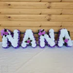 **NANA Artificial Silk Funeral Flowers – Custom 4-Letter Name Tribute Wreath** Honor the memory of a beloved family member with the **NANA Artificial Silk Funeral Tribute Wreath**, designed to commemorate anyone with a **4-letter name**. Whether it’s **NANA**, **MAMA**, **PAPA**, or any other 4-letter name, this elegant wreath offers a personal and lasting tribute. Crafted from high-quality artificial silk flowers, this wreath is ideal for graveside memorials or ceremonies, serving as a beautiful and respectful expression of love and remembrance. --- ### **Key Features:** #### **Customizable 4-Letter Name Tribute** - Personalize your wreath with any **4-letter name** such as **NANA**, **MAMA**, **PAPA**, or **DADA**. - Each letter is carefully crafted from premium **artificial silk carnations**, ensuring a vibrant and lifelike display. #### **Premium Quality Materials** - Made with high-quality **artificial silk flowers** that retain their beauty and freshness, even over time. - Finished with **ribbon edging** and optional **posy clusters**, adding sophistication and elegance to your memorial wreath. #### **Wide Selection of Color Options** - Choose from **8 beautiful carnation colors** including White, Red, Pink, Yellow, Purple, and more. - Select from **14 ribbon colors**, such as Baby Pink, Gold, Navy, Burgundy, Silver, and more, for a unique and personalized look. - Optional **posy clusters** available in contrasting or complementary colors to enhance your tribute. #### **Ideal Size for Memorial Display** - The wreath is designed to create a striking, yet respectful tribute, measuring **XX inches wide x XX inches high**. - Supplied with a **florist frame stand** for secure and stable placement at gravesides or memorial services. #### **Free Personalized Message Card** - Includes a **complimentary message card and holder**, allowing you to include a personal note of remembrance for your loved one. --- ### **How to Personalize Your Tribute:** 1. **Select the Name**: Choose “NANA” or any **4-letter name** for your wreath. 2. **Pick Carnation Colors**: Choose from **8 vibrant carnation colors** such as White, Red, Yellow, Pink, and more. 3. **Choose Ribbon Colors**: Select from **14 ribbon colors** to complement or contrast with the carnation choice. 4. **Add Posy Clusters**: Add optional posy clusters in coordinating or contrasting colors for extra beauty and personalization. 5. **Provide Details**: Use the “Personalization” box to specify the name, carnation color, ribbon color, and posy cluster choices. --- ### **Examples of Custom Designs:** - **Classic Tribute:** Name – NANA Carnations – White Ribbon – Gold Posy – Purple - **Vibrant Memorial:** Name – MAMA Carnations – Red Ribbon – Baby Pink Posy – White - **Soft Remembrance:** Name – PAPA Carnations – Yellow Ribbon – Silver Posy – Blue --- ### **Why Choose This Tribute?** - **Fully Customizable:** Choose colors and personalize the name to create a unique and special tribute. - **Lifelike and Durable:** Premium silk flowers ensure the wreath remains beautiful and vibrant for years to come. - **Timeless and Elegant Design:** A meaningful and respectful way to celebrate and remember your loved one. --- ### **Important Notes:** - **Color Variations:** Slight differences in flower and ribbon shades may occur due to lighting conditions during photography. - **Floral Substitutions:** Occasionally, substitutions may be necessary for flower or posy styles to maintain design integrity and quality. --- ### **A Beautiful and Lasting Tribute** The **NANA Artificial Silk Funeral Flowers Tribute Wreath** is a thoughtful and meaningful way to honor a loved one’s life. Whether commemorating **NANA**, **MAMA**, **PAPA**, or any 4-letter name, this customizable wreath offers a heartfelt, lasting expression of love and remembrance.